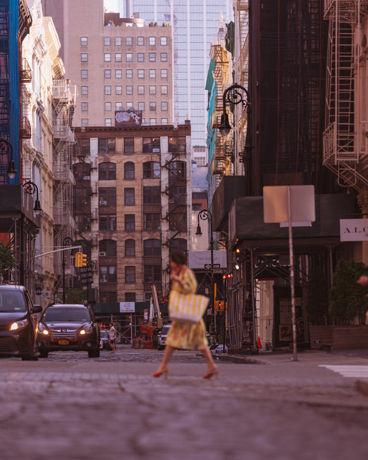 Woman with shopping bag crossing a cobblestone street in SoHo, New York
