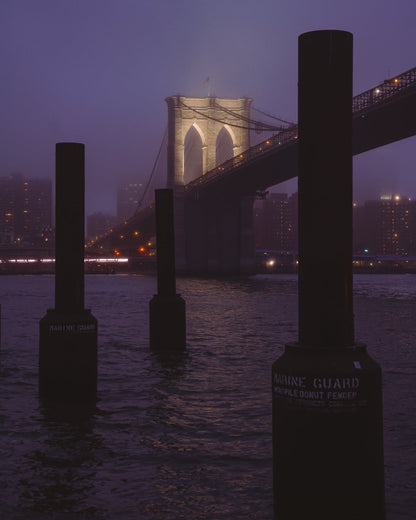 The Brooklyn Bridge lit up during a foggy blue hour sunset