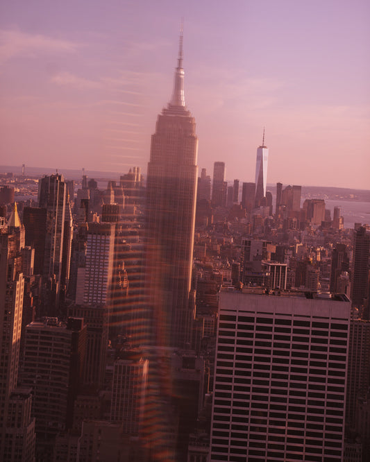 The Empire State Building reflected over the skyline during a pink sunset
