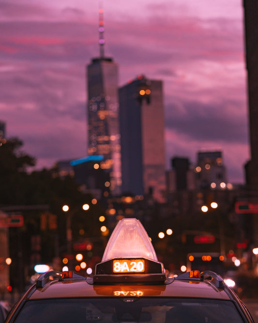 Close up of the numbers on top of a yellow cab in New York CIty during a bright pink sunset