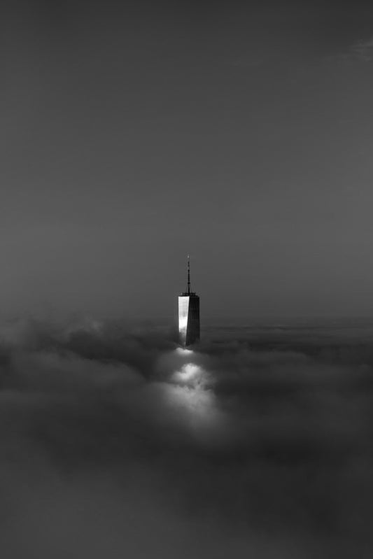 The top of the World Trade Center tower peeking out from dense fog across New York City during sunrise